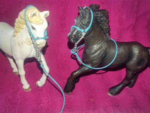 Ein weißes und braunes Schleichpferd mit blauen Halfter 