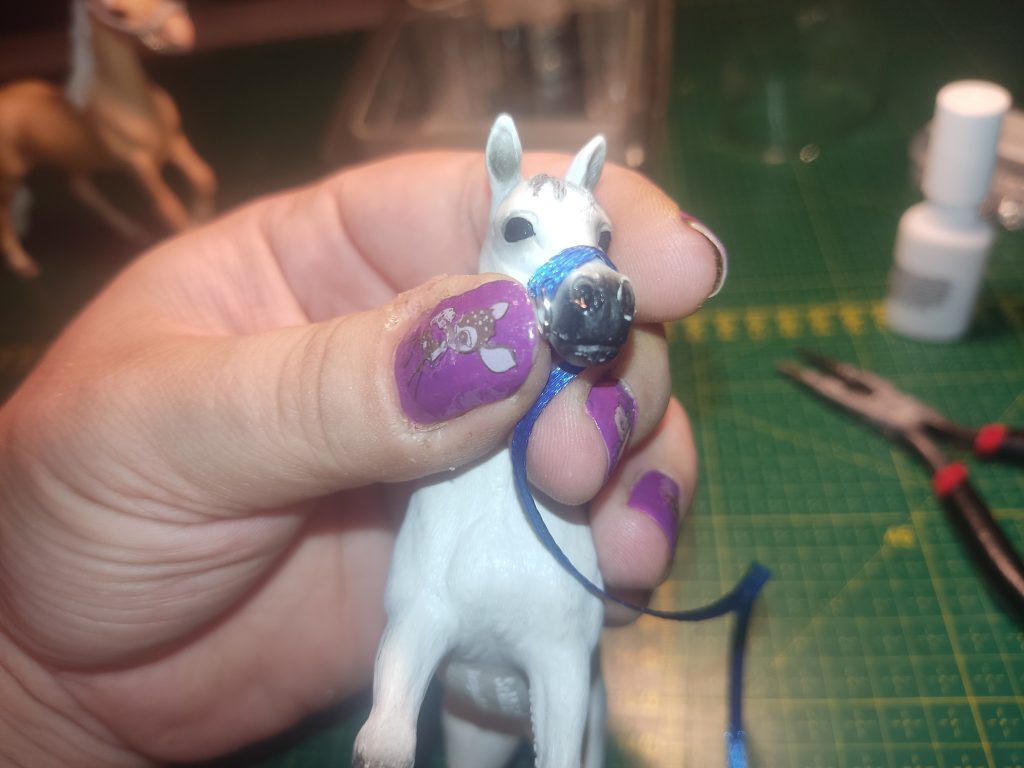 Blaues Satinband wird an Pferdeschnauze von Schleich Schimmel ausgemessen