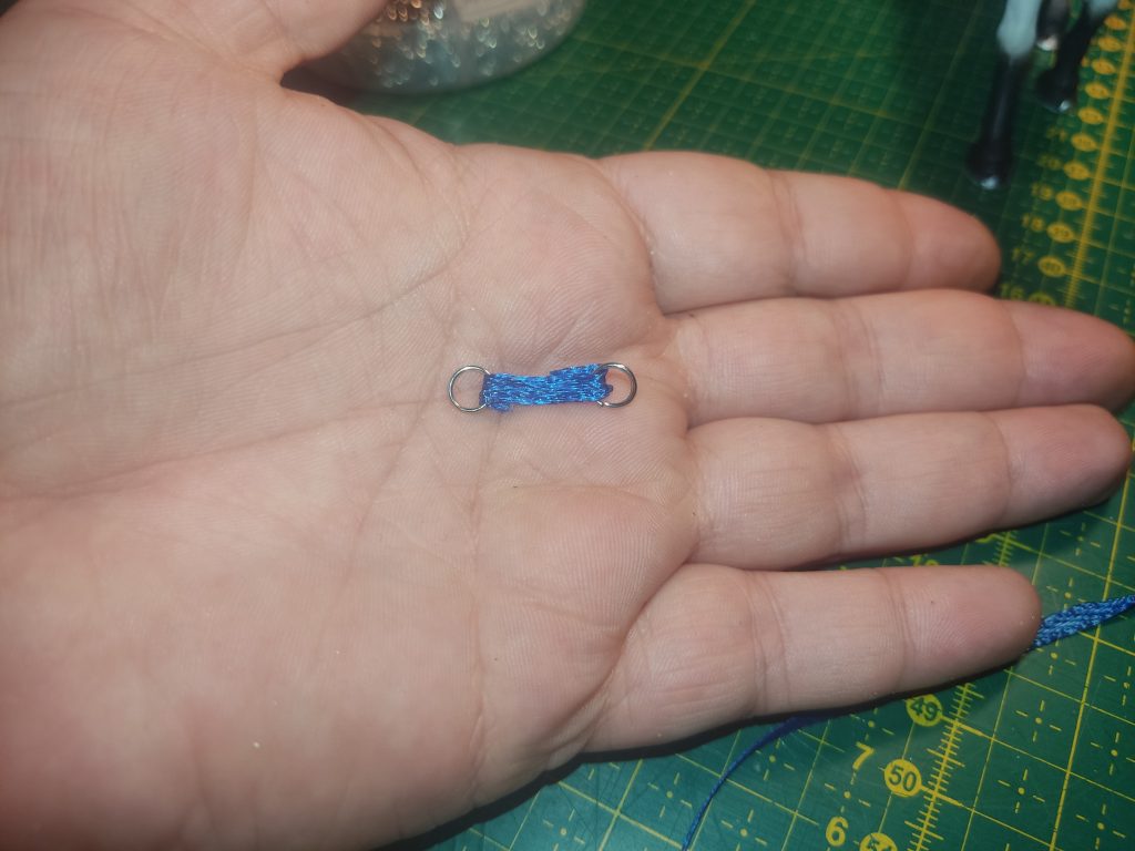 Ein winziges Stück blaues Satinband mit 2 Ringen an den Enden