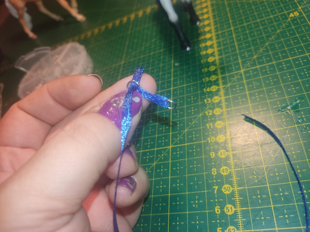 Blaues Satinband wird durch einen Ring gefädelt