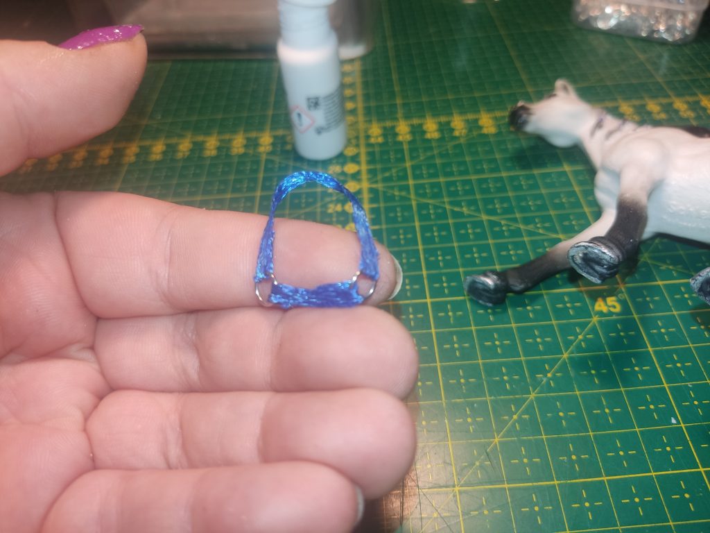 Ein blaues dünnes Satinband mit 2 Ringen verbunden in einer Hand