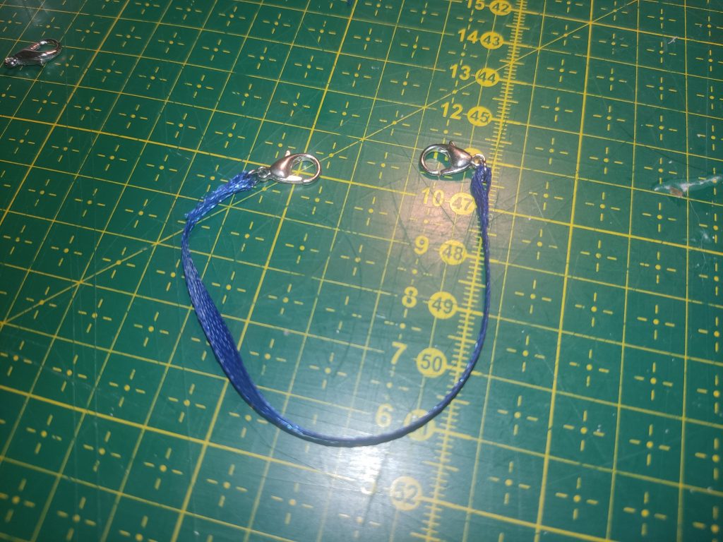 Ein Stück dunkelblaues Satinband mit 2 Haken