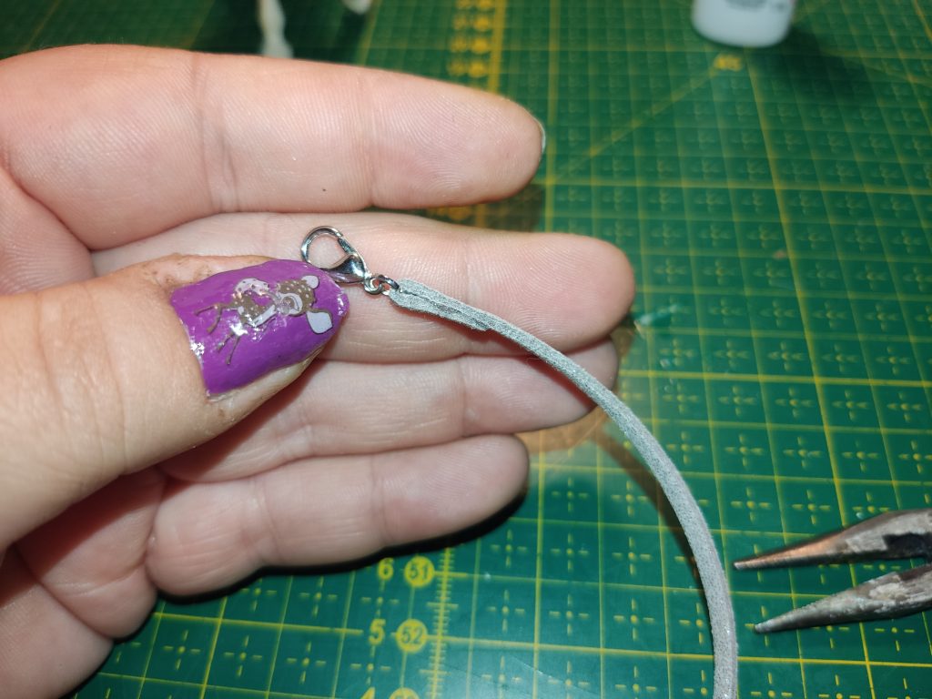 Eine Hand hält eine Schnur mit kleinem Haken